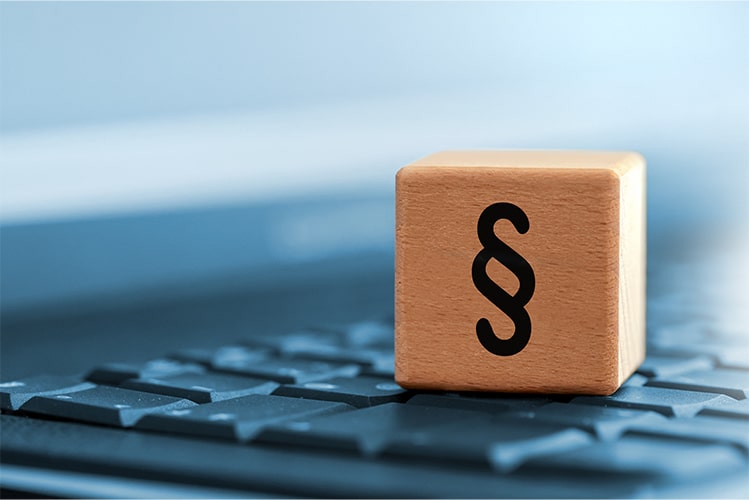 Tastatur mit einem Würfel mit Paragraphen-Symbol, symbolisiert die Erreichung der BAIT-Compliance und die Umsetzung regulatorischer Anforderungen.