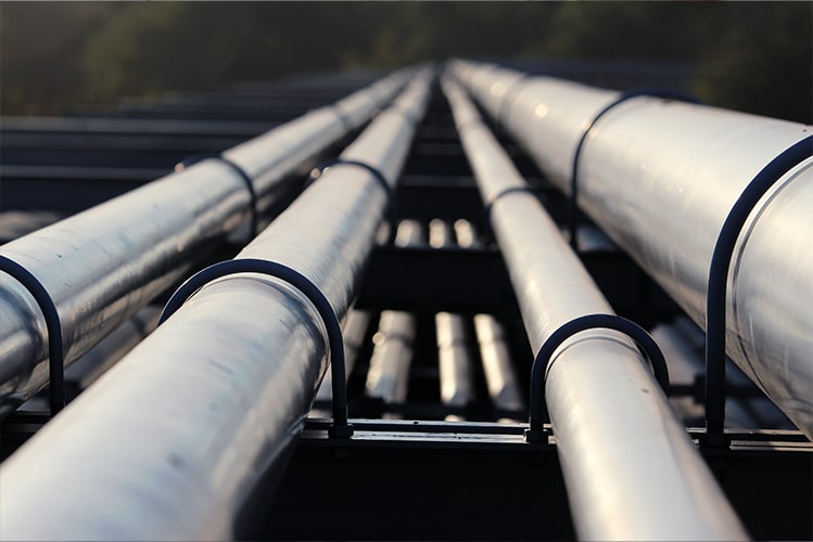Metallrohre symbolisieren die vernetzten und optimierten CI/CD-Pipelines, die für VAIT-Konformität und automatisierte Prozesse im Außendienstsystem angepasst wurden.