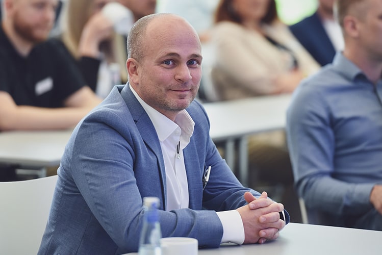 Mitarbeiter der BROCKHAUS AG im Anzug lächelt in die Kamera, symbolisiert die erfolgreiche Digitalisierung des Prozesses zur Finanzberatung und Förderermittlung.