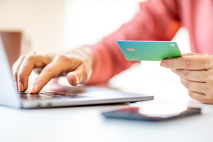 Frau mit Kreditkarte vor Laptop nutzt Banking Portal für Ratenzahlungen
