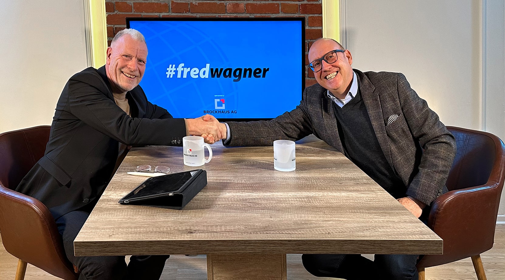 Prof. Dr. Fred Wagner und Frank Kettnaker schütteln sich die Hände in einem modernen Büro