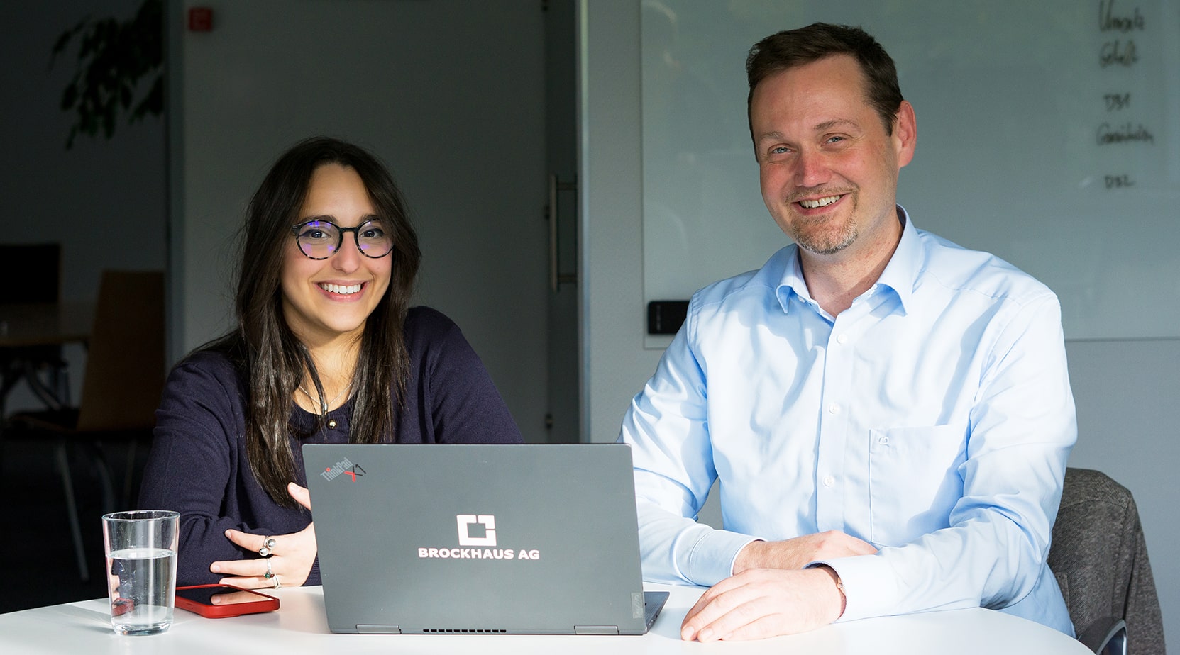 Aya Rbib und Matthias Besenfelder sitzen vor einem Laptop und besprechen strategische Entscheidungen während der Aktion Be the Boss.