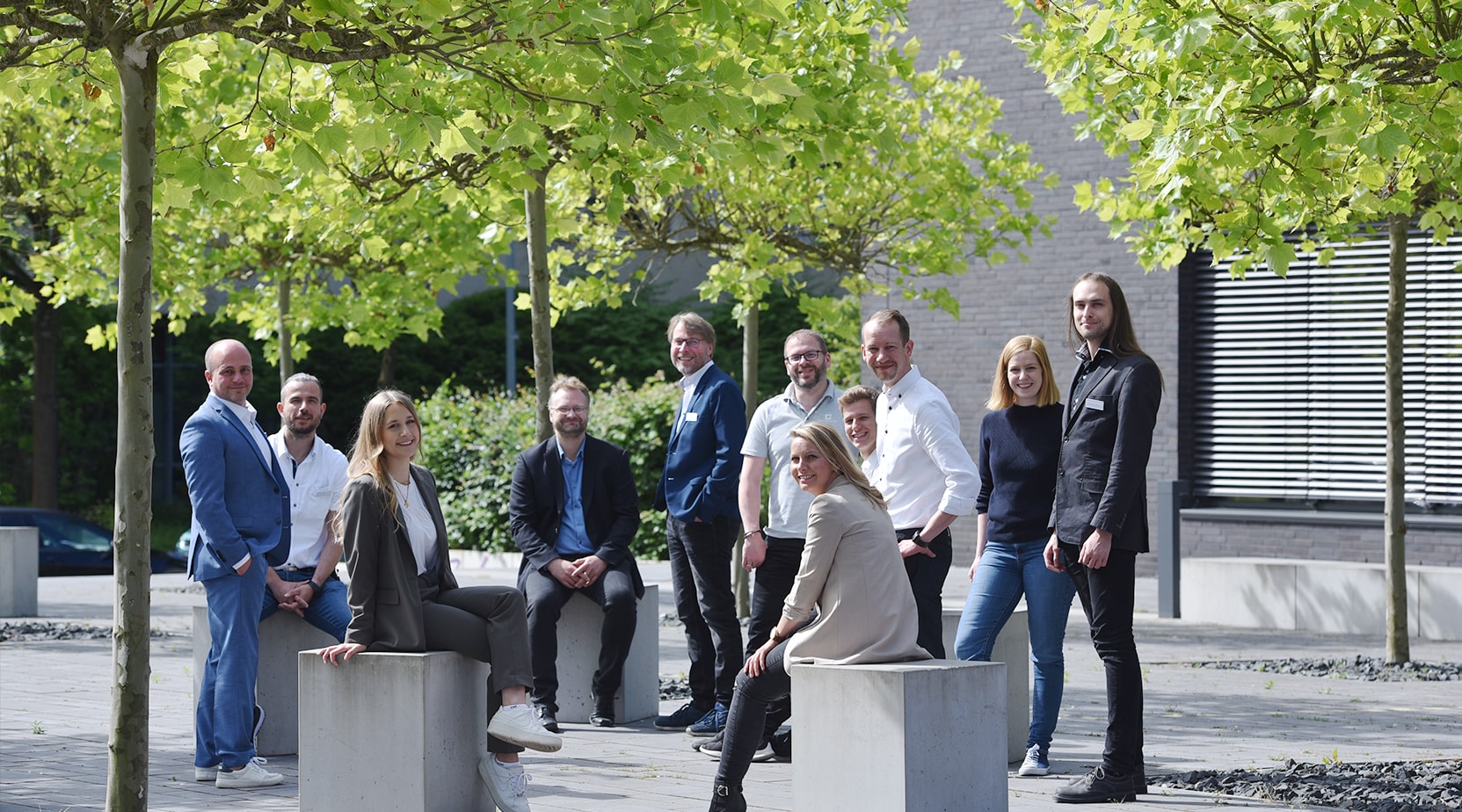Ein engagiertes Team von BROCKHAUS AG-Mitarbeitern steht draußen in einem informellen Kreis zusammen, um Dezentrale Führung und die Auswirkungen des digitalen Wandels auf Unternehmen zu besprechen.