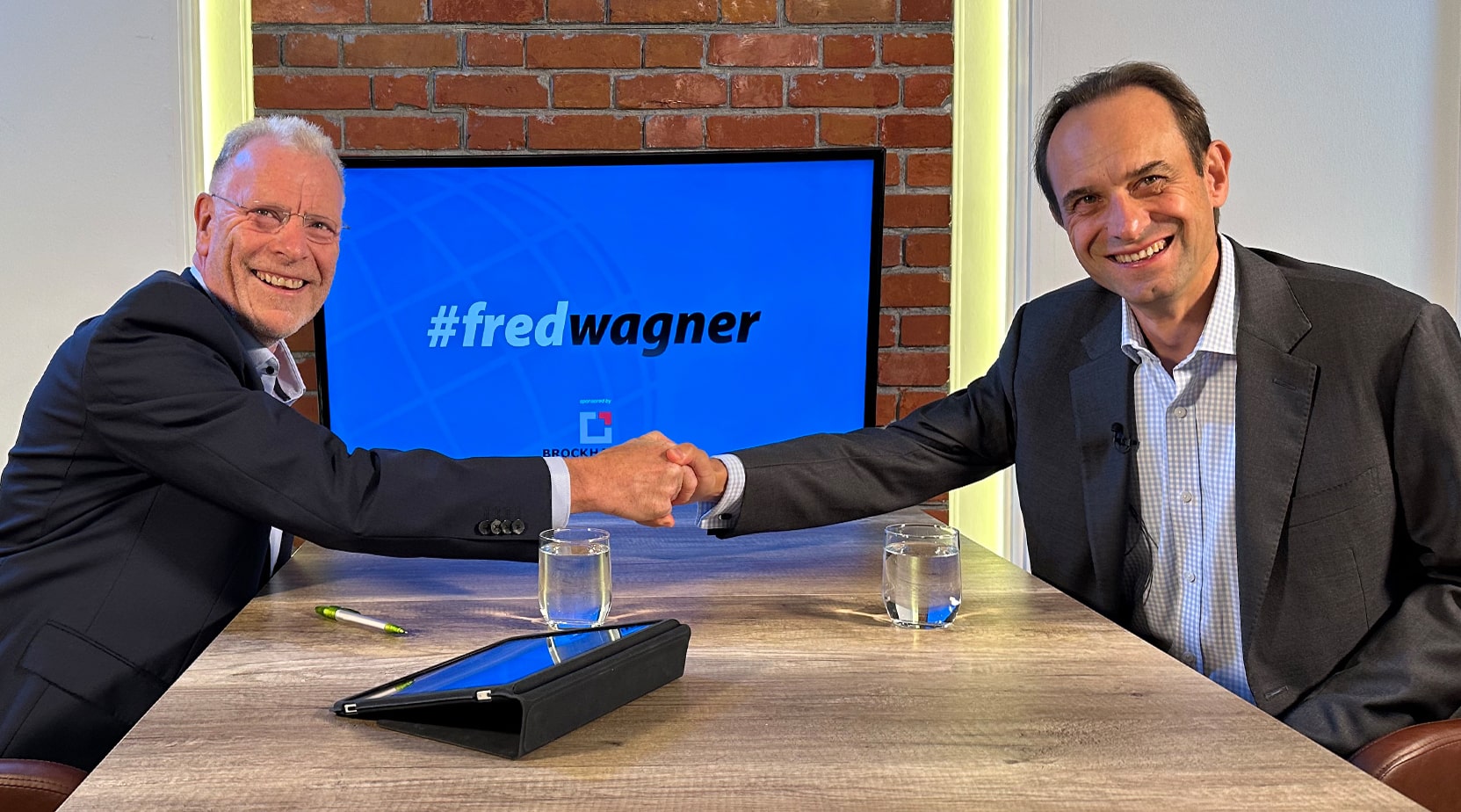 Prof. Dr. Fred Wagner und Mark Branson reichen sich über den Interviewtisch die Hand.