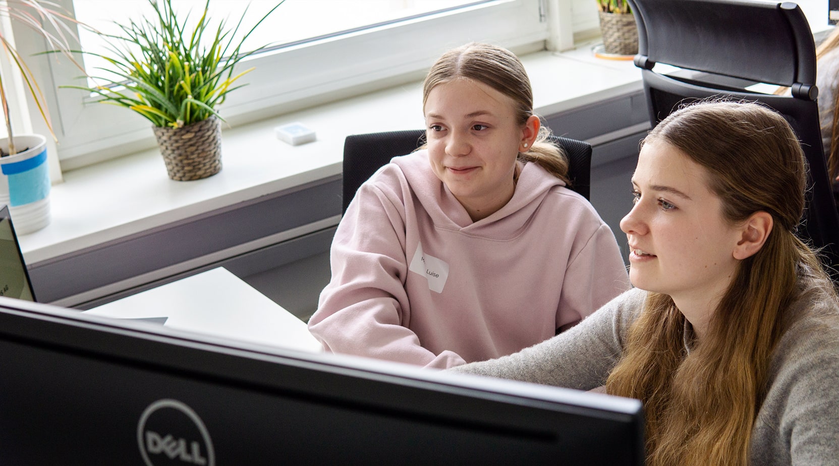 Zwei Mädchen sitzen gemeinsam am Computer und arbeiten an ihrer App im Rahmen des Girls Day der BROCKHAUS AG.