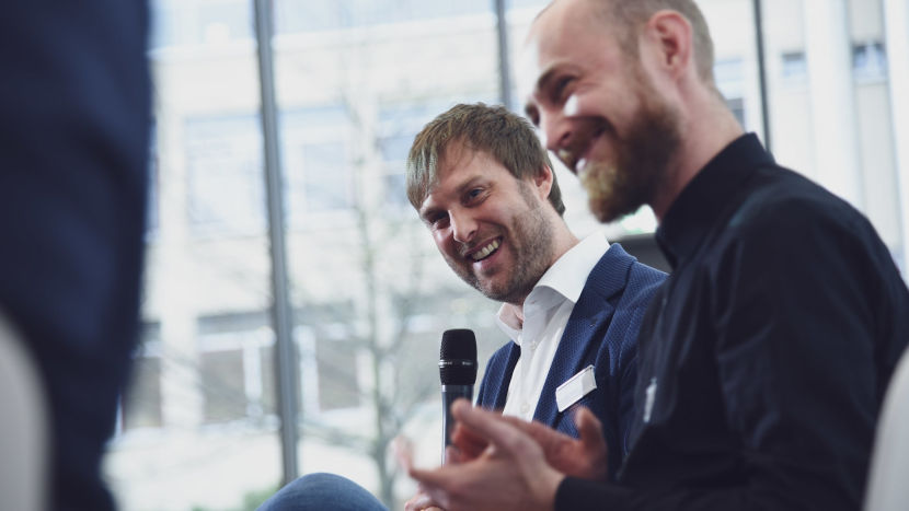 Guido Nippe (Head of IT-Consulting) hält ein Mikrofon in der Hand und lächelt seinen Gegenüber an