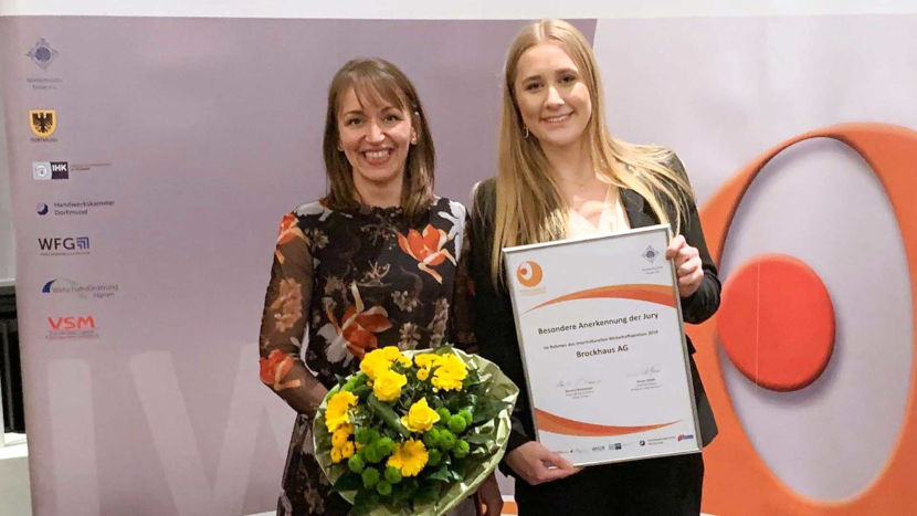 Mitarbeiterinnen Marie Sonne und Maria Beerwerth halten bei der Preisverleihung die Auszeichnung des multikulturellen Forums in den Händen
