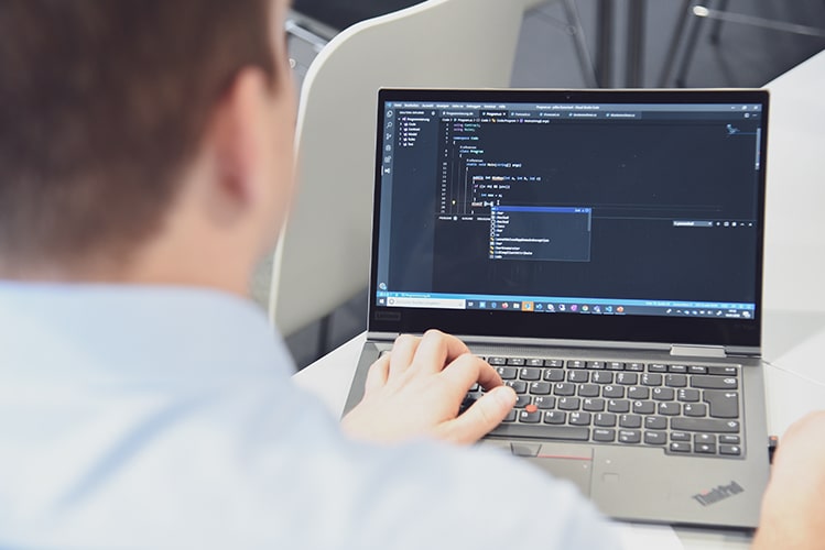 Ein Mitarbeiter sitzt vor dem aufgeklappten Laptop und gibt aktuelle Werte ein