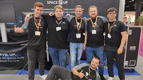 Mitarbeitende der BROCKHAUS AG zeigen sich stolz auf dem Messestand auf der gamescom