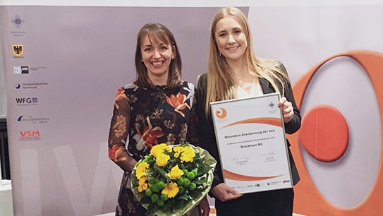 Mitarbeiterinnen Marie Sonne und Maria Beerwerth halten bei der Preisverleihung die Auszeichnung des multikulturellen Forums in den Händen